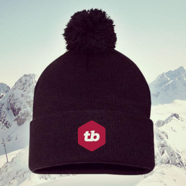 black toque with pompom and the red TB logo embroidered on the brim of the hat